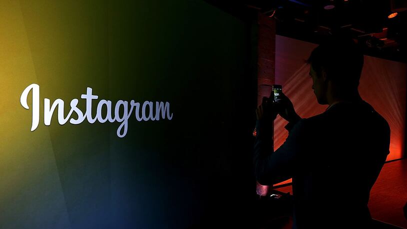 MENLO PARK, CA - JUNE 20:  An attendee takes a photo of the instagram logo during a press event at Facebook headquarters on June 20, 2013 in Menlo Park, California. Facebook announced that its photo-sharing subsidiary Instagram will allow users to take and share video.  (Photo by Justin Sullivan/Getty Images)