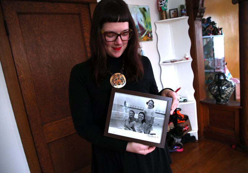Morgan Richardson is seen at home in Chicago on Tuesday, Jan. 29, 2019, with a photo of herself with her twin sister Lauren, left, and mother Deborah. Richardson, who was conceived via In Vitro Fertilization (IVF), submitted a DNA sample to the DNA testing company 23andMe to find out about her ancestry. Almost immediately, she started discovering half-siblings from across the U.S., all from the same anonymous sperm donor her mom used. (Terrence Antonio James/Chicago Tribune)