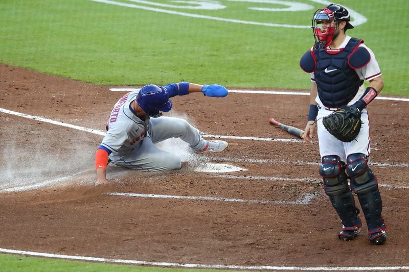 New York Mets Michael Conforto scores past Atlanta Braves catcher Travis D’Arnaud on a 2-run single by Robinson Cano’ to take a 3-0 lead over the Atlanta Braves during the third inning Monday, Aug. 3, 2020, in Atlanta.    