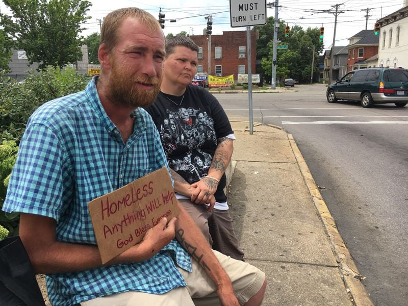 Matthew and Melissa Emrick said they are waiting on public assistance and student loans, but in the meantime raise money holding a sign on Keowee Street near the intersection with Wayne Avenue. “This is what I have to do to get us out of here,” she said.