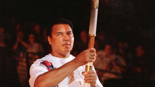 Former boxer Muhammad Ali, a Gold Medal winner in boxing in the 1960 Olympics when his name was Cassius Clay, holds up the torch prior to lighting a device that would carry the flame up the cauldron, during the opening ceremonies of the XXVI Centennial Olympic Games in Atlanta, July 19. - RTXGNH6