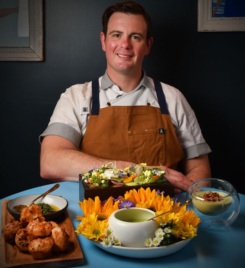 Southern Belle and Georgia Boy executive chef Joey Ward with his spring vegetable recipes: Spring Vidalia Greens Chimichurri alongside a Brazilian cheese bread, Spring Vidalia Pão de Queijo (left); Green Garlic and Carrot Top Dressing (lower center); and Strawberry and Almond Gazpacho with Georgia Olive Farms Olive Oil (right). (Styling by Joey Ward / Chris Hunt for the AJC)