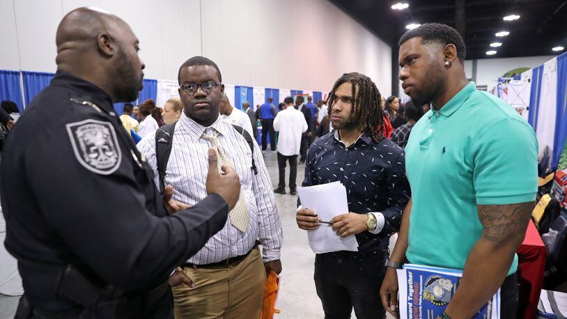 DeKalb County Police detective Keith Lee, left, talks with Daniel Townsend, of Decatur, second from left, Qunchez Childs, center, and William Burson, both of Atlanta, during the 15th Annual Jobs Fair at the Georgia International Convention Center Friday, April 13. JASON GETZ for the AJC