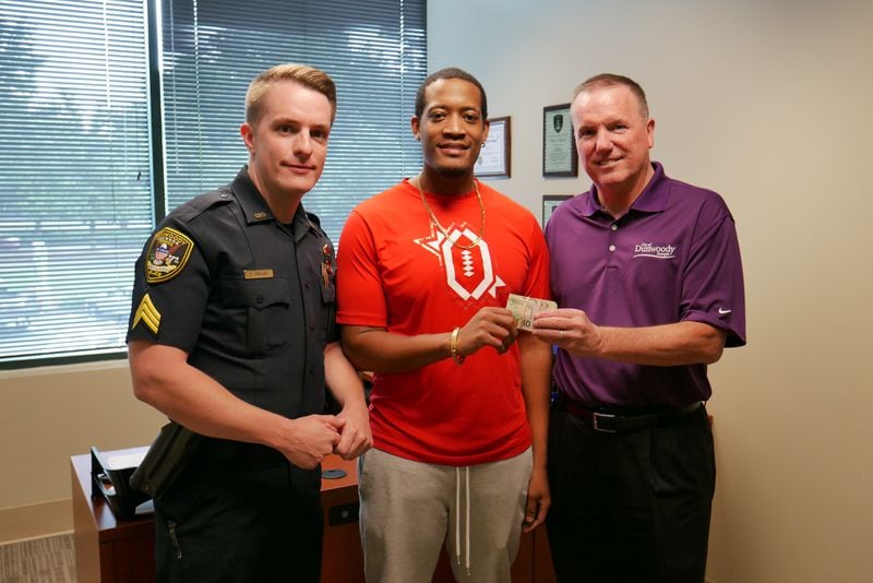 Randrell Lewis (center) poses with Dunwoody police Sgt. Robert Parsons (left) and Chief Billy Grogan after Lewis returned $2,100 he took from an armored truck spill on I-285.