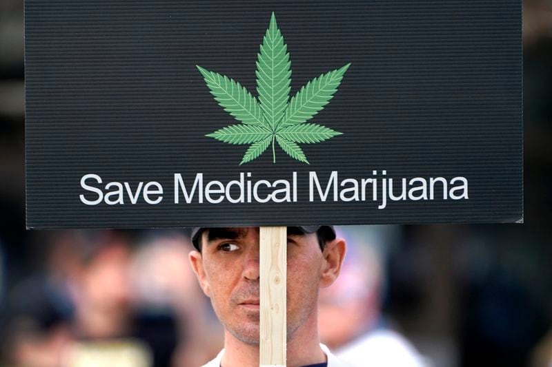 FILE - A protester who supports medical marijuana holds a sign outside the Augusta Civic Center where the state legislature was meeting, Wednesday, April 28, 2021, in Augusta, Maine. A federal proposal to reclassify marijuana as a less dangerous drug has raised the hopes of some pot backers that more states will embrace cannabis. (AP Photo/Robert F. Bukaty, File)