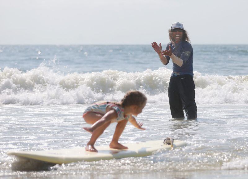 Atsushi "Hot Sushi" Yamada claps as a student surfs into shore Thursday during Hot Sushi's Happy Surf Camp Aloha on Tybee Island. Yamada was happy to be back in the water working with children just two days after being bitten by a shark near this very spot.