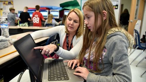Forsyth County’s Chestatee Elementary School teacher Joy Hall helps fourth-grader Raine Wilson with a writing assignment during class in this AJC file photo.