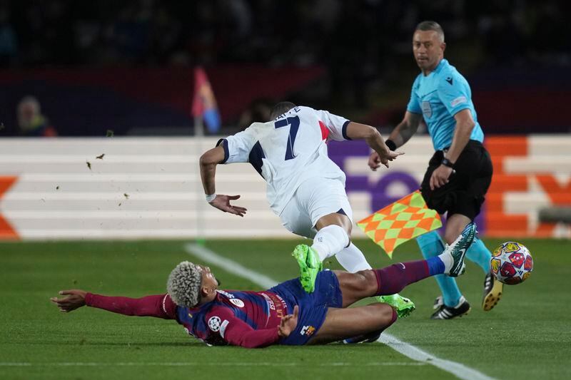 PSG's Kylian Mbappe, top, is challenged by Barcelona's Ronald Araujo during the Champions League quarterfinal second leg soccer match between Barcelona and Paris Saint-Germain at the Olimpic Lluis Companys stadium in Barcelona, Spain, Tuesday, April 16, 2024. (AP Photo/Emilio Morenatti)