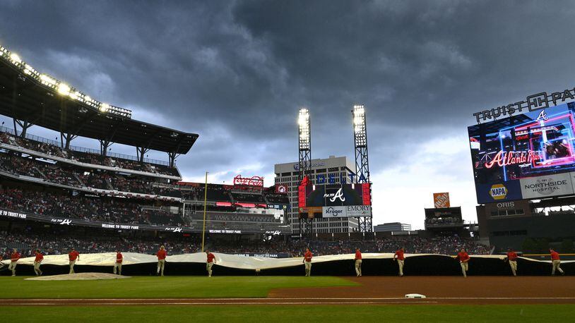 The grounds crew pulls out the tarp as dark clouds fill the sky before Atlanta Braves home game against Los Angeles Angels at Truist Park on Friday, July 22, 2022. (Hyosub Shin / Hyosub.Shin@ajc.com)