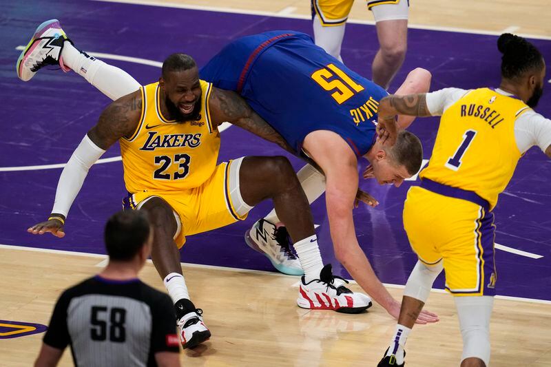Denver Nuggets center Nikola Jokic (15) falls on top of Los Angeles Lakers forward LeBron James (23) during the second half of Game 3 of an NBA basketball first-round playoff series in Los Angeles, Thursday, April 25, 2024. (AP Photo/Ashley Landis)