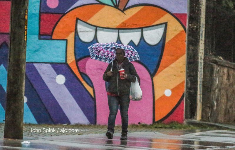 Rhonda Wilson needed an umbrella on her walk along the 500 block of Ponce de Leon Avenue early Monday. JOHN SPINK / JSPINK@AJC.COM
