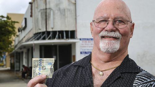 Steve Morris stands outside the old El Cid bar with half of a dollar bill that 40 years ago he and Joe Whitehead wrote “4/4/2016” on, ripped in half and kept. The two friends vowed to meet and have a drink at the Cid 40 years in the future. (Lannis Waters / The Palm Beach Post)