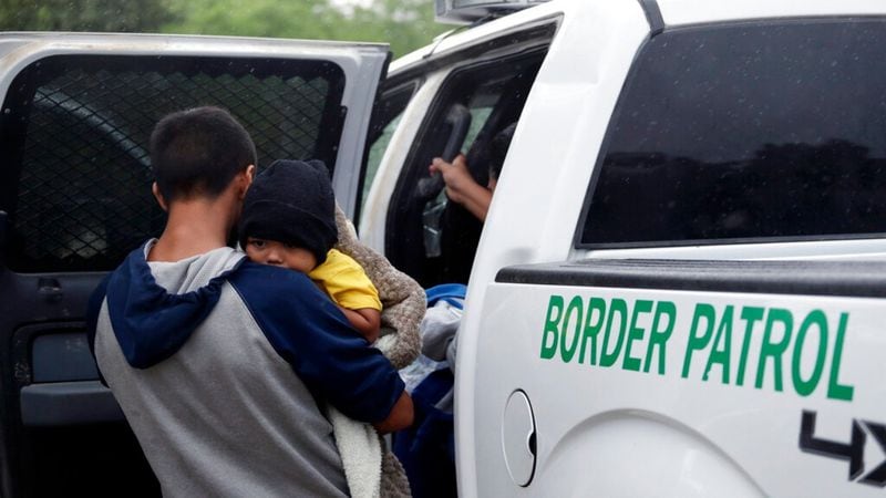 In this Thursday, March 14, 2019, photo, families who crossed the nearby U.S.-Mexico border near McAllen, Texas are placed in a Border Patrol vehicle. Immigration authorities say they expect the ongoing surge of Central American families crossing the border to multiply in the coming months.