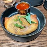 The lamb hand pie at Ela has a seriously meaty filling in richly seasoned gravy and melted cheese. (Angela Hansberger for The Atlanta Journal-Constitution)