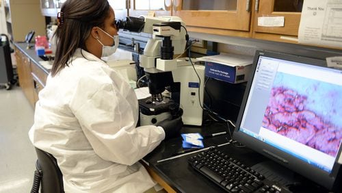 Scientist Lanisha Gittens uses a microscope as she works on evidence in the serology lab at the GBI crime laboratory in late 2015. KENT D. JOHNSON/ kdjohnson@ajc.com
