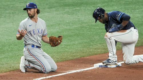 Texas Rangers' Charlie Culberson (left) looks to the Texas dugout for affirmation after Tampa Bay Rays' Manuel Margot (right) stole third base during the fourth inning Thursday, April 15, 2021, in St. Petersburg, Fla. (Steve Nesius/AP)