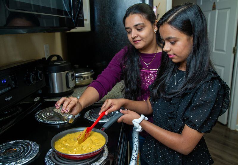 Aesha Bhatt (right) cooks with her mother, Hita, in their Johns Creek home. 
PHIL SKINNER FOR THE ATLANTA JOURNAL-CONSTITUTION.