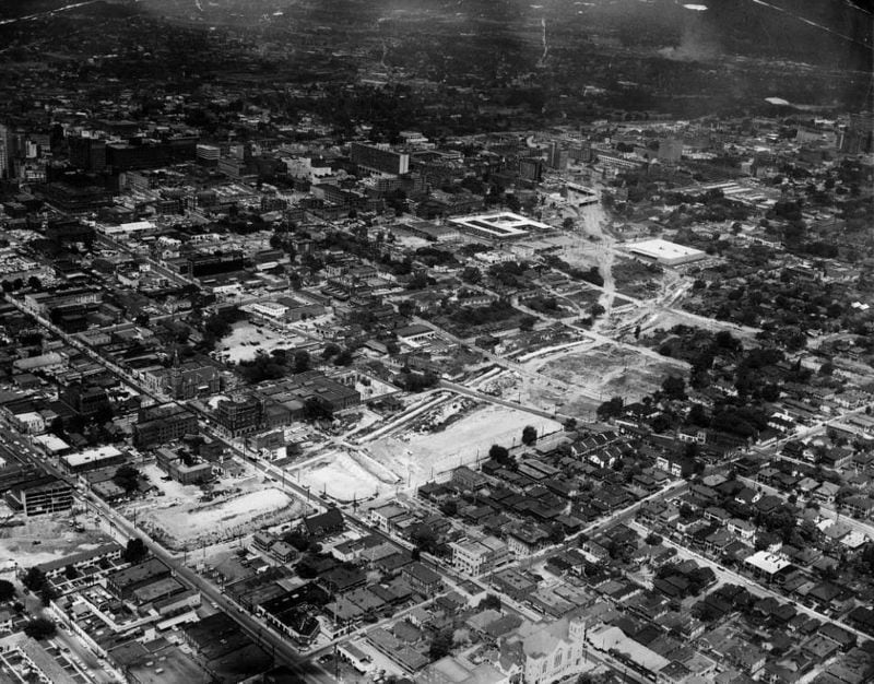 The path of the future Downtown Connector carves through the Sweet Auburn neighborhood in this aerial image from 1958. Looking northwest, Edgewood and Auburn Avenues are visible in the foreground at bottom left. Landmarks such as Big Bethel AME Church, the Oddfellows Building and the Butler Street YMCA are visible left of the demolition. (AJC Archive at GSU Library / AJCPov01-011)