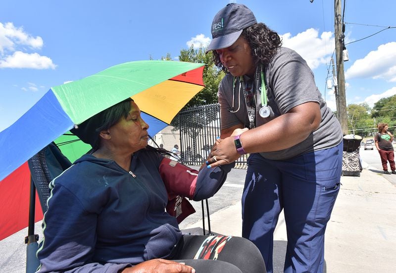 Stephanie Dotson, a nurse on the Street Medicine team, checks Johnsie Holloway’s blood pressure. Holloway is 65 and has been living on the streets for several years. She was one of more than a dozen women of all ages lining Ethel Street outside the Atlanta Day Shelter for Women and Children. Holloway, who suffers from high blood pressure, says she can’t make a move into an apartment. “The girls here need me,” she says. (Hyosub Shin / Hyosub.Shin@ajc.com)