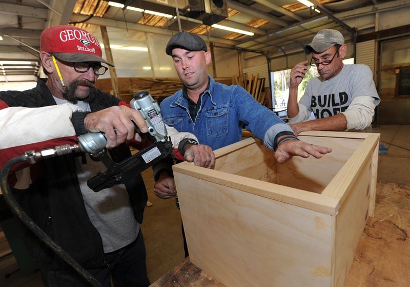 Roger "TC" Curtis , Brian Preston and Carl A Carlson assemble a piece of furniture. Credit: Staff file photo
