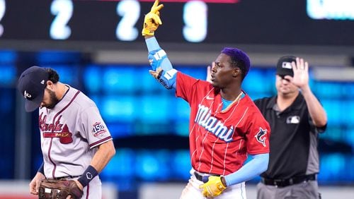 Miami Marlins' Jazz Chisholm Jr. (center) reacts after hitting a double during the fifth inning against the Atlanta Braves, Sunday, July 11, 2021, in Miami.  At left is Atlanta Braves shortstop Dansby Swanson. (Lynne Sladky/AP)