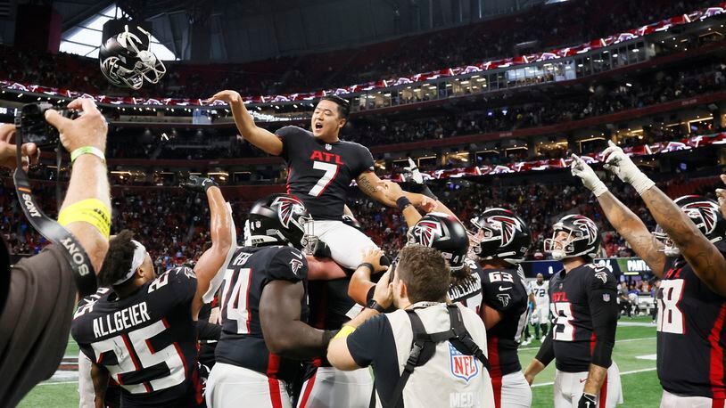 Falcons kicker Younghoe Koo tosses his helmet as he celebrates with teammates after making the winning field goal in overtime Sunday against the Panthers in Atlanta. The Falcons won 37-34. (Miguel Martinez / miguel.martinezjimenez@ajc.com)