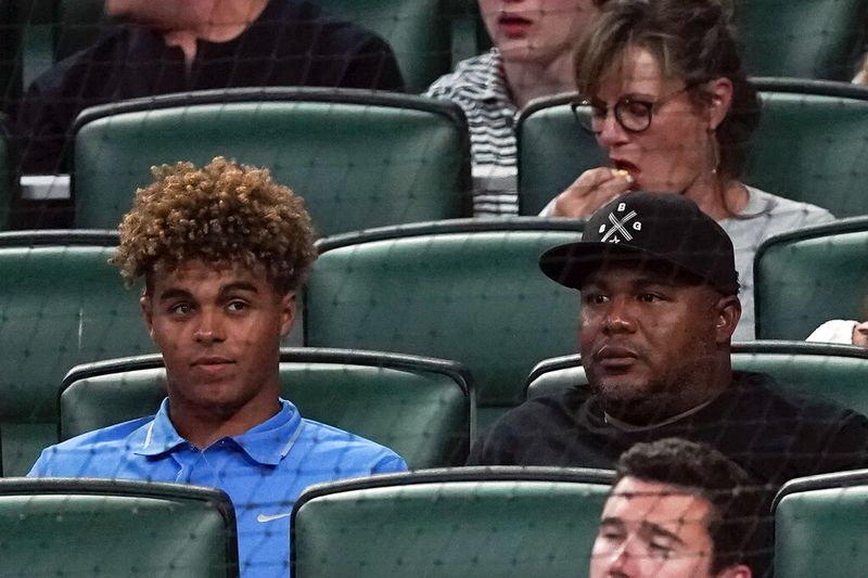 Former Atlanta Braves outfielder Andruw Jones, right, sits with his son Druw during a baseball game between Oakland Athletics and the Braves Tuesday, June 7, 2022, in Atlanta. Druw is a top prospect. (AP Photo/John Bazemore)