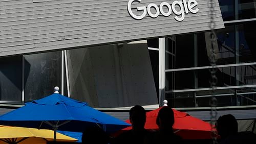 People walk by a Google sign on the campus in Mountain View, California. Google co-founders Larry Page and Sergey Brin are relinquishing control of parent company Alphabet to current Google CEO Sundar Pichai.