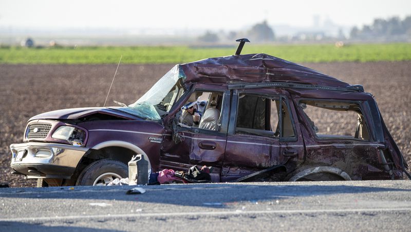 A CHP officer looks inside a mangled SUV which was carrying 25 people when it collided with a semi-truck, killing 13 on Highway 115 near the Mexican border on Tuesday in Holtville, California. (Gina Ferazzi/Los Angeles Times/TNS)