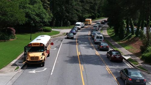 Fulton County Schools bus stops on Powers Ferry Road in Sandy Springs on Wednesday, May 23, 2018. A phrase added to a 15-page bill late in the Georgia legislative session has caused panic among officials responsible for getting children to and from school safely. HYOSUB SHIN / HSHIN@AJC.COM