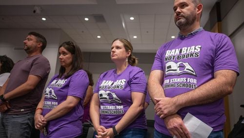 At a Cobb school board meeting in July, demonstrators wore shirts calling for the district to "ban bias, not books" after a teacher was removed from her classroom for reading a book that challenges gender norms to fifth graders. At the board's most recent meeting in April, Superintendent Chris Ragsdale announced that four more books are being removed from school libraries for containing inappropriate content. (Katelyn Myrick / AJC file photo)