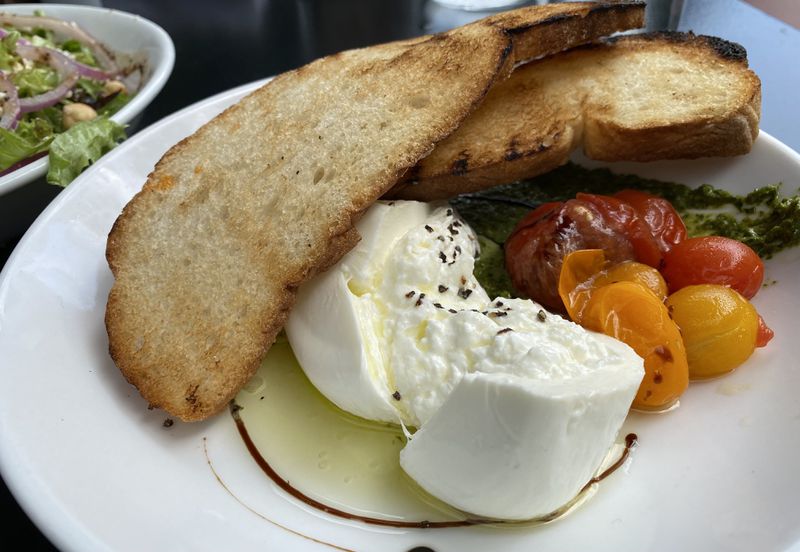 House-made burrata with cherry tomatoes and a garlic-laced basil pesto is among shareable plates at City Winery. (Ligaya Figueras / ligaya.figueras@ajc.com)