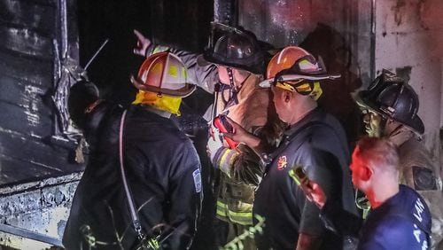 Atlanta fire crews examine a hole in a fire-burned floor at a rooming house on the corner of Burbank and Martin Luther King Jr. drives. A firefighter was injured when he stepped through a hole in the floor Thursday morning.