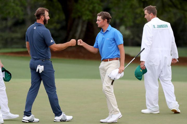 April 9, 2021, Augusta: Dustin Johnson, left, and Tyler Strafaci fist bump after their second round on the eighteenth hole during the Masters at Augusta National Golf Club on Friday, April 9, 2021, in Augusta. Curtis Compton/ccompton@ajc.com