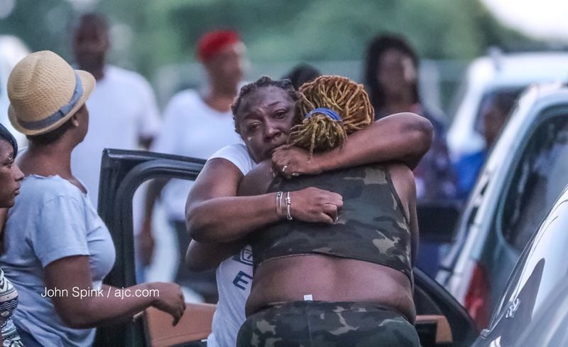 Family members console each other on Simmons Street in northwest Atlanta after a man was gunned down in an apparent shootout. JOHN SPINK / JSPINK@AJC.COM