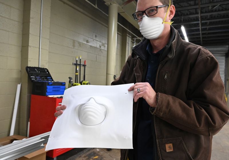 Engineer Whit Costley holds a sheet being formed into the shape of new N95 mask. He used a temporary prototype molding station at ThermoPore Materials Corporation, a plastics manufacturer in Newnan that received government approval to make a new type of N95 that utilizes a different filtration material. (Hyosub Shin / Hyosub.Shin@ajc.com)