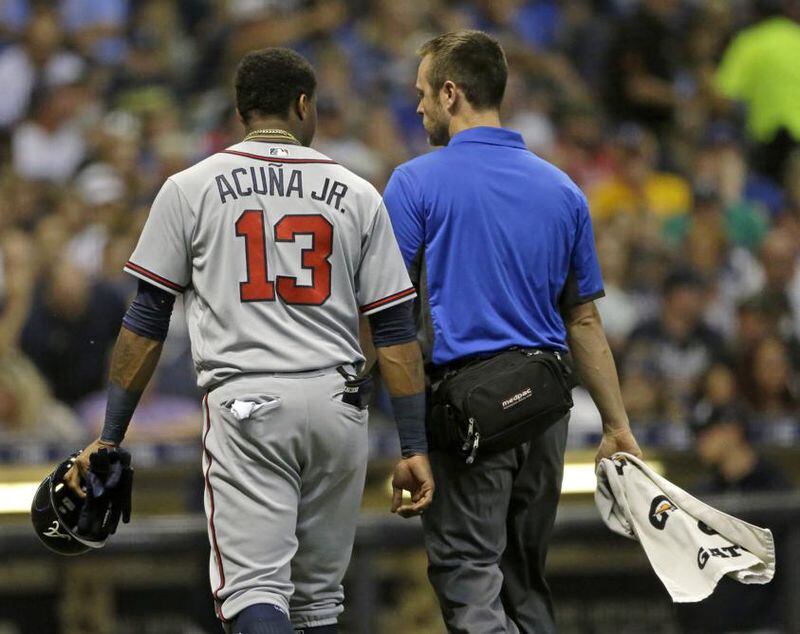 Ronald Acuna walks to the dugout with a trainer after feeling tightness in his groin running out an infield hit in the seventh inning Friday. (AP Photo/Aaron Gash)