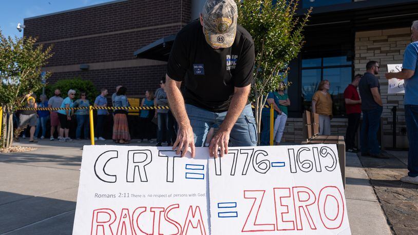 Rick Cox, who has a son in the Cherokee County school system, holds signs outside of the school board chambers before a meeting Thursday night, May 20, 2021. The building reached capacity and the people in line behind Cox were not allowed in for the start of the meeting. (Ben Gray for The Atlanta Journal-Constitution)