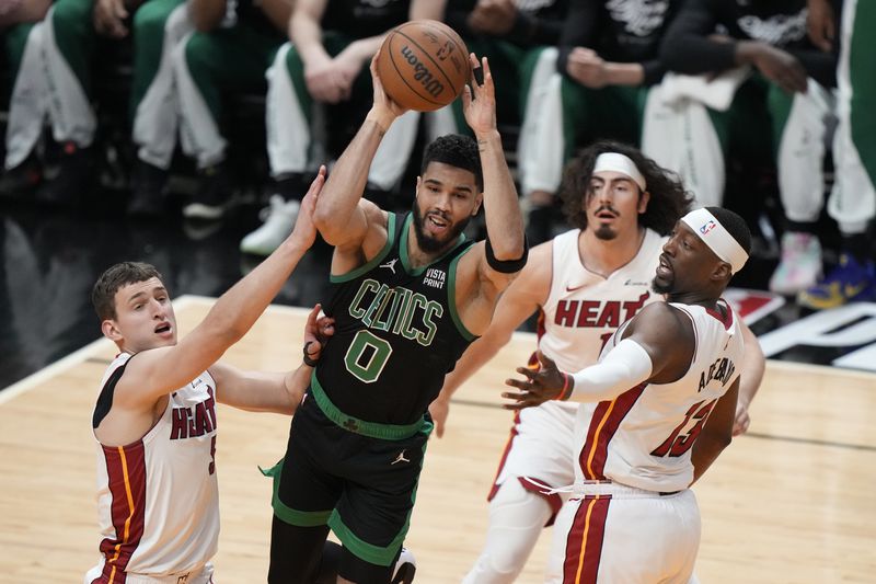 Boston Celtics forward Jayson Tatum (0) passes past Miami Heat forwards Nikola Jovic, left, Jaime Jaquez Jr., second from right, and center Bam Adebayo (13) during the first half of Game 3 of an NBA basketball first-round playoff series, Saturday, April 27, 2024, in Miami. (AP Photo/Wilfredo Lee)