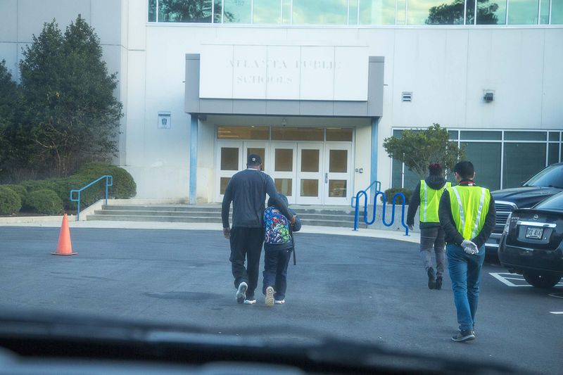 Harper-Archer Elementary School staff walk Corbin into the school after retrieving him from his grandmother, Wednesday, February 26, 2020.  (ALYSSA POINTER/ALYSSA.POINTER@AJC.COM)