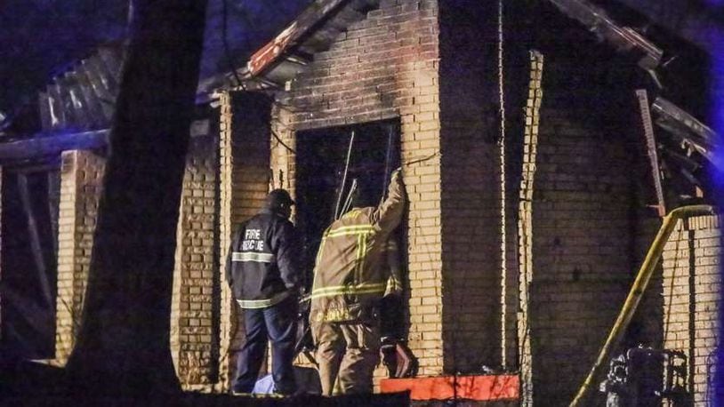 Firefighters examine what remains of an East Point home in the 2900 block of Hogan Road that was gutted by a fire shortly after midnight on Tuesday, March 15, 2016. Firefighters arrived at 12:18 a.m. and found heavy fire and smoke coming from the front and side of the house. It took about three hours for them to contain the blaze, and they continued to battle hot spots at 6 a.m. The roof and floor in the home collapsed, making it dangerous for firefighters to enter. JOHN SPINK / JSPINK@AJC.COM
