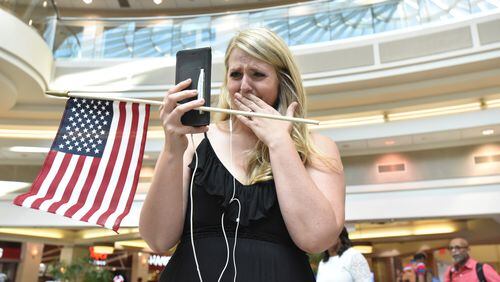 Lindsey Eastwood can’t hide her emotion as she broadcasts livestream video of the flash mob to welcome her husband, Jon Eastwood, at Hartsfield-Jackson International Airport’s domestic terminal atrium on Friday, Aug. 3, 2018. Weather forced a cancellation for Jon’s flight, but he made it in a day later for their in-person reunion. (Photo: HYOSUB SHIN / HSHIN@AJC.COM)