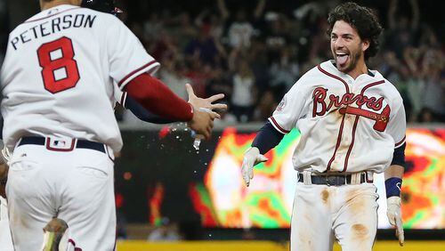 Jace Peterson and the rest of the Braves rush the field to mob Dansby Swanson after his walk-off single to beat the Padres on Monday. Curtis Compton/ccompton@ajc.com