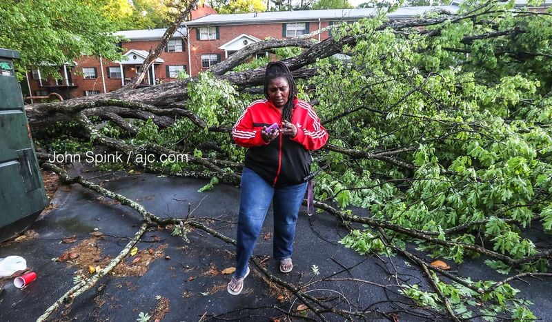 Monique Best, an Uber driver, walks away from her crushed car after a tree fell at the Lexington Apartments on Kentucky Court in East Point. 