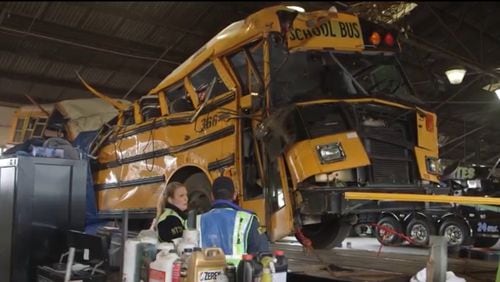 National Transportation Safety Board members with the hulk of the school bus that crashed in Chattanooga on Monday, killing at least five children. (Screen capture from NTSB video)