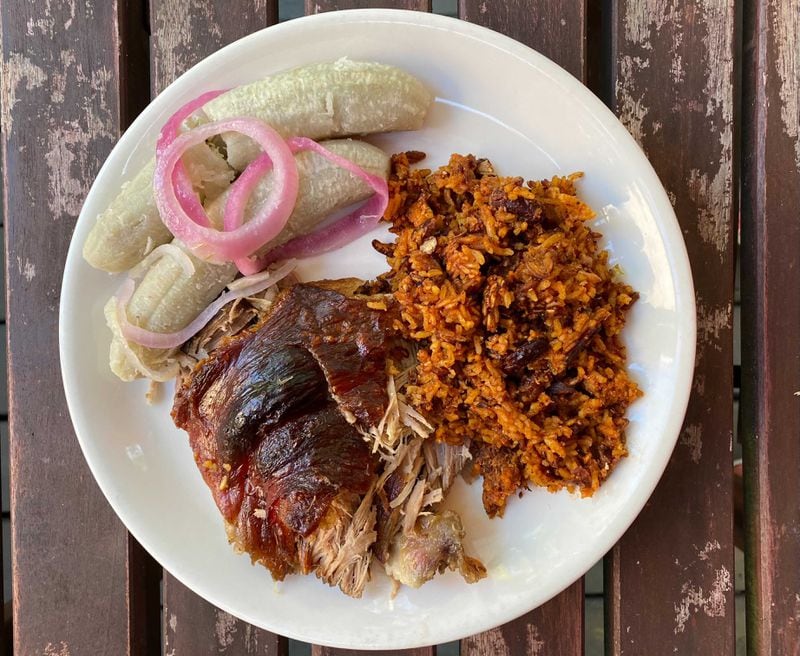 The steam table at NYC Bodega is filled with a daily rotation of Dominican dishes, including roasted pork shoulder, scorched rice known as pegao and boiled green bananas with pickled red onion. (Ligaya Figueras / ligaya.figueras@ajc.com)