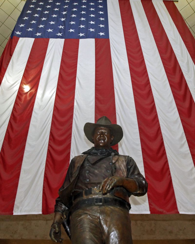 A bronze statue of late actor John Wayne stands before a four-story high U.S. flag at John Wayne Orange County Airport in Santa Ana, California. Officials want the statue removed.