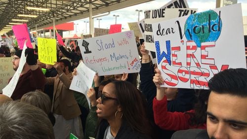 Protesters carry signs Sunday at Atlanta Hartsfield-Jackson International Airport. They are protesting new limits on refugees and immigration imposed by President Donald Trump. (Scott Trubey / AJC)