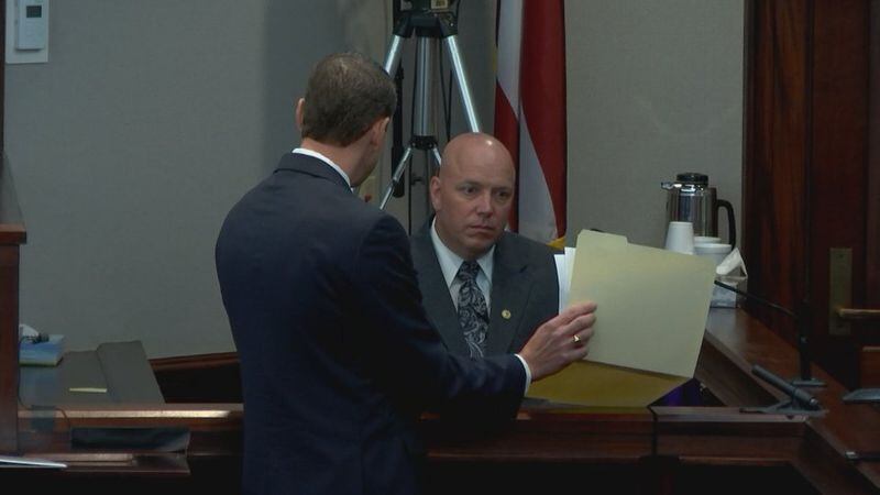 Detective Carey Grimstead is shown some photos by the prosecution during the murder trial of Justin Ross Harris at the Glynn County Courthouse in Brunswick, Ga., on Thursday, Oct. 27, 2016. Grimstead's testimony -- his third for this trial -- involved details about the state of Harris' SUV during the police investigation. (screen capture via WSB-TV)