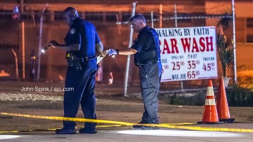 Officers search for evidence after two groups started shooting in the middle of Donald Lee Hollowell Parkway on Tuesday morning. A 19-year-old man was shot in the back.